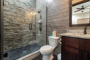 Full bathroom featuring tile walls, vanity, a stall shower, and a ceiling fan
