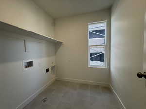 Washroom with hookup for a washing machine, electric dryer hookup, and light tile patterned flooring