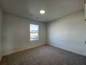 Carpeted spare room featuring baseboards