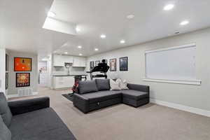 Living area featuring light colored carpet, recessed lighting, and bar