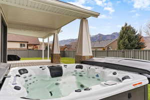 Fenced backyard featuring a hot tub, a mountain view, and a patio area