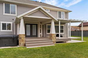 Back of property featuring french doors, a patio, roof with shingles, and a hot tub