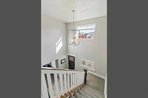 Staircase with carpet flooring, a chandelier, and a high ceiling
