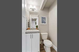 Half bathroom with vanity and dark wood-style floors