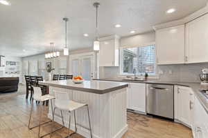 Kitchen with a kitchen bar, a center island, dishwasher, pendant lighting, and open floor plan