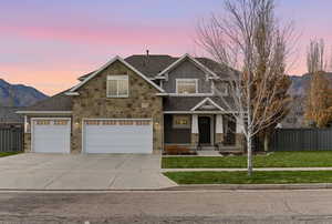 Craftsman-style house featuring board and batten siding, a mountain view, concrete driveway, a shingled roof, and stone siding