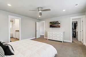 Bedroom featuring a walk in closet, light carpet, recessed lighting, a ceiling fan, and connected bathroom