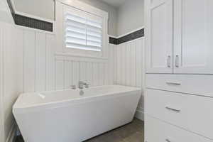 Full bath with a freestanding bath and light tile patterned flooring