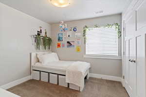 Bedroom featuring light colored carpet and a textured ceiling