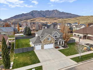 View of front of property featuring a mountain view, driveway, covered porch, stone siding, and a residential view