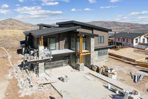 Back of house with a mountain view, a patio, and stone siding