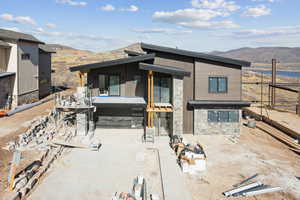 Back of property with a mountain view, stone siding, and a patio