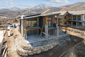 Back of property featuring a patio area, a mountain view, and stone siding