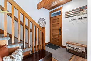 Foyer featuring a baseboard heating unit, stairway, wood finished floors, and a wood ceiling with exposed beams