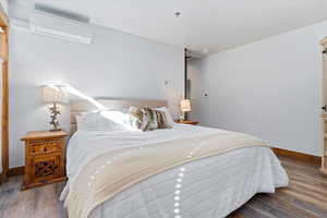 Bedroom featuring dark wood finished floors and a wall mounted AC