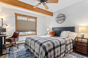 Bedroom featuring wood finished floors, beam ceiling, a baseboard radiator, and ceiling fan