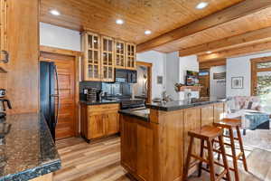 Kitchen with a kitchen bar, open floor plan, glass insert cabinets, light wood-style flooring, and backsplash