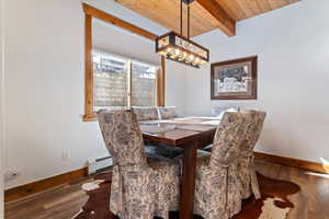 Dining space with a wood ceiling with exposed beams, dark wood-type flooring, a baseboard radiator, and a chandelier