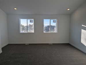 Unfurnished room with dark colored carpet, healthy amount of natural light, and recessed lighting