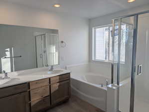 Full bathroom featuring a shower stall, a bath, double vanity, dark wood-style floors, and recessed lighting