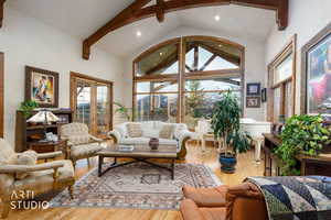 Living area with beam ceiling, wood finished floors, and high vaulted ceiling