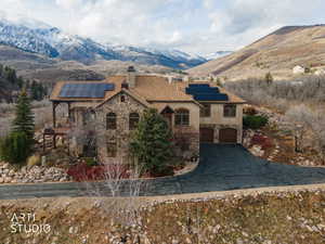 Mediterranean / spanish house featuring stone siding, a chimney, a mountain view, and solar panels