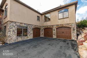Mediterranean / spanish home featuring stone siding, stucco siding, an attached garage, and driveway