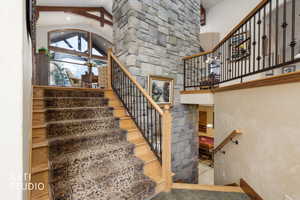 Stairs with high vaulted ceiling, beam ceiling, and tile patterned floors