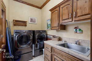 Washroom with ornamental molding, cabinet space, separate washer and dryer, and light tile patterned flooring