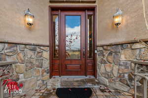 Doorway to property featuring stone siding and stucco siding