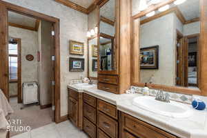 Full bathroom with crown molding, double vanity, and light tile patterned floors