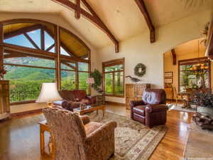 Living room featuring beamed ceiling, high vaulted ceiling, wood finished floors, a chandelier, and a mountain view