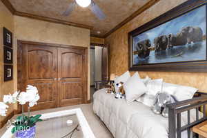 Carpeted bedroom featuring a closet, ornamental molding, a ceiling fan, and a textured wall