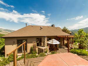 Back of property featuring a mountain view, a patio, stucco siding, and roof with shingles