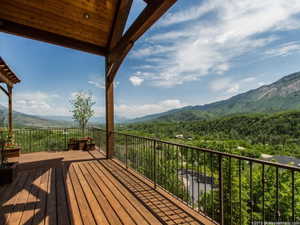 Deck with a view of trees and a mountain view