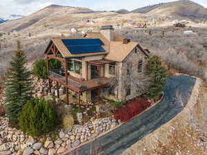 View of front of house with a chimney, stone siding, solar panels, and a deck with mountain view