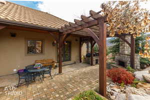 View of patio / terrace with a pergola, an outdoor stone fireplace, outdoor dining space, and area for grilling