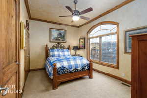 Bedroom with light carpet, crown molding, and a ceiling fan