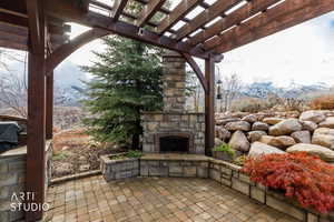 View of patio / terrace with a mountain view, a pergola, and an outdoor stone fireplace