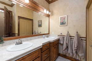 Bathroom with double vanity, crown molding, and light tile patterned floors