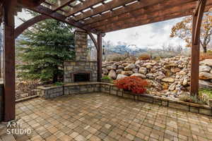 View of patio featuring a pergola and an outdoor stone fireplace