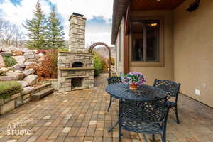 View of patio / terrace featuring an outdoor stone fireplace and outdoor dining space