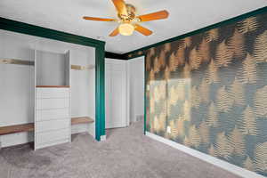 Unfurnished bedroom featuring carpet, a closet, a ceiling fan, and a textured ceiling