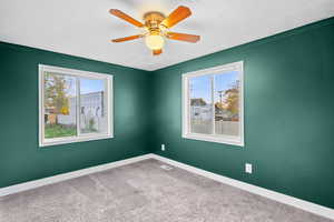 Unfurnished room with carpet flooring, healthy amount of natural light, a ceiling fan, a textured ceiling, and ornamental molding