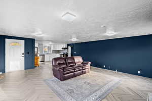 Living area featuring baseboards and a textured ceiling