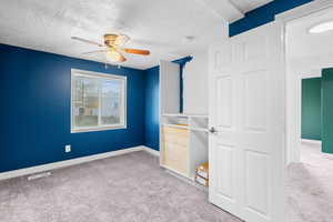 Unfurnished bedroom with light colored carpet, a textured ceiling, and a ceiling fan