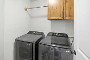 Laundry area featuring separate washer and dryer and cabinet space