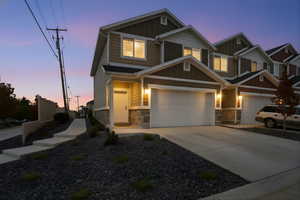 Craftsman-style home with board and batten siding, stone siding, and concrete driveway