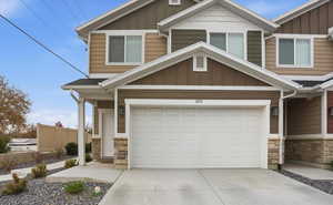 Craftsman-style house featuring stone siding, driveway, and board and batten siding