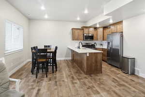 Kitchen featuring stainless steel appliances, brown cabinets, a peninsula, recessed lighting, and light wood finished floors